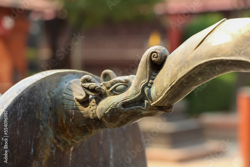 Close-up view of bronze Yali (Hindu mythological creature with trunk of elephant) head decoration located in one of courtyards (bahals) in Lalitpur city, Nepal. Soft focus. Culture of India. photo