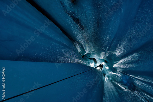 A cave explorer hangs on a rope inside a moulin on the Aletsch Glacier. photo
