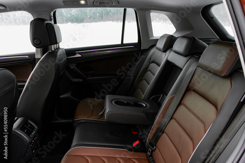 Modern SUV car inside. Leather black back passenger seats in modern luxury car with opened armrest. Comfortable leather seats.