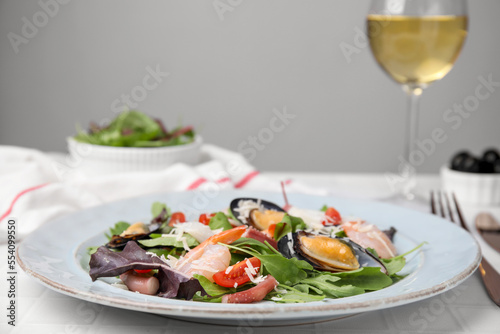 Plate of delicious salad with seafood on white tiled table