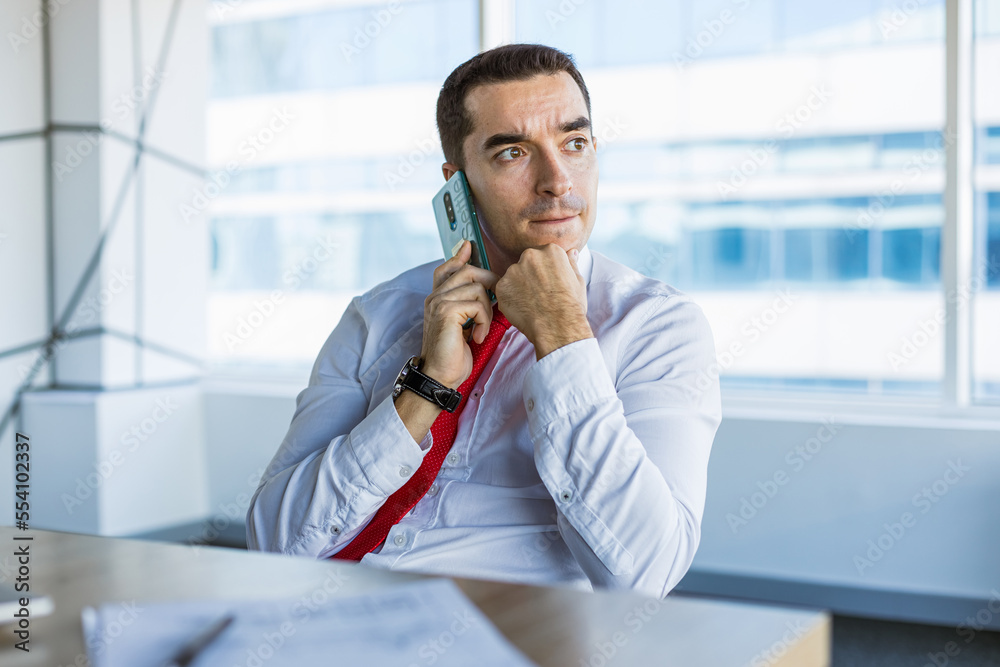 Portrait of a business young successful man in a modern office sitting at a table Portrait of a business young successful man in a modern office sitting at a table