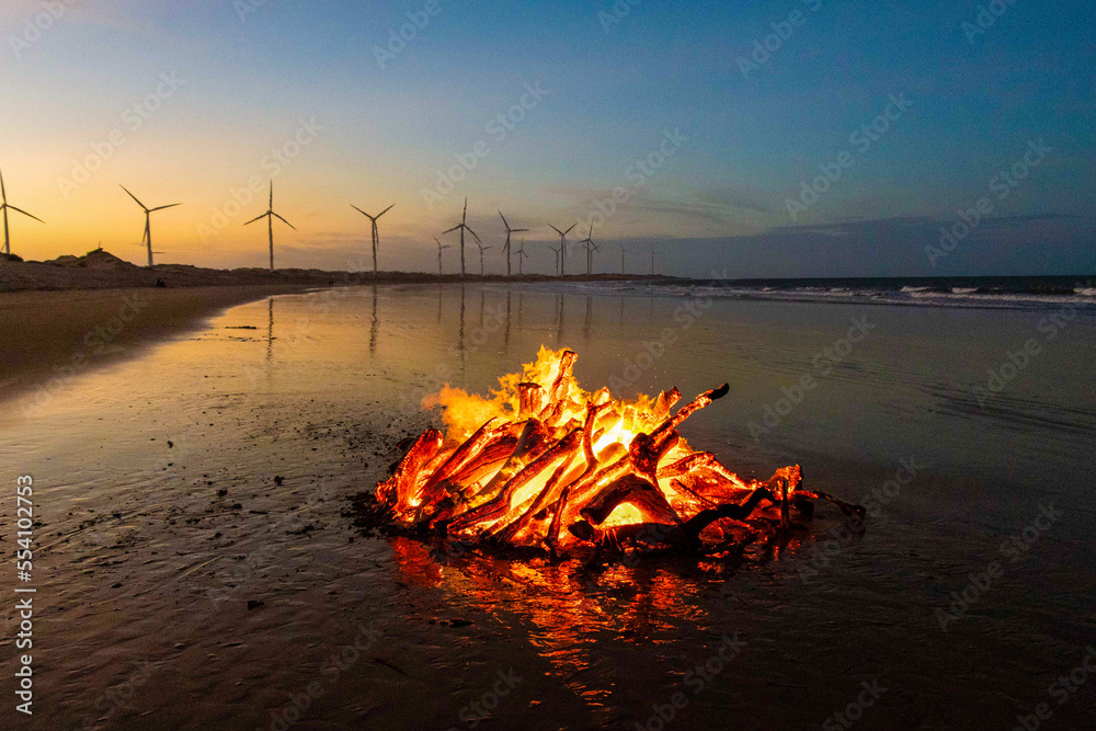 Fogueira acesa na praia e torre de energia eólica, em Icaraí Ceará - obrazy, fototapety, plakaty 