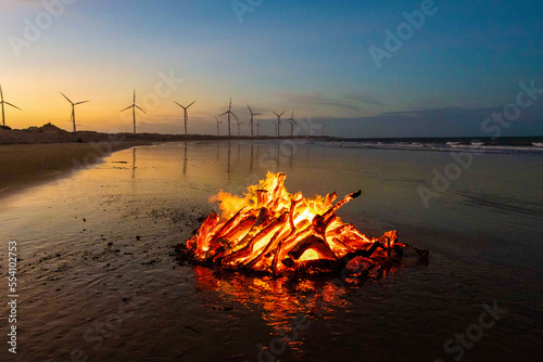 Fogueira acesa na praia e torre de energia eólica, em Icaraí Ceará