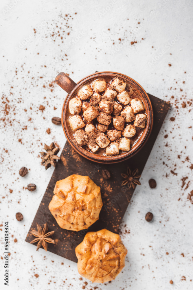 Hot chocolate drink with marshmallows in a cup and sweet bakery eclair dessert sprinkled with cocoa powder, cinnamon stick and star anise, top view Hot chocolate drink with marshmallows in a cup and sweet bakery eclair dessert sprinkled with cocoa powder, cinnamon stick and star anise, top view