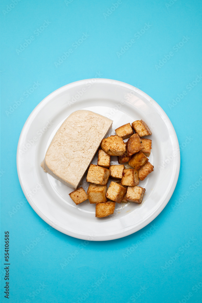 raw tofu block on white small dish on yellow raw tofu block on white small dish on yellow