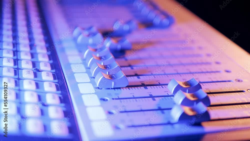 Sound producer moving switches on the mixing console at audio recording studio