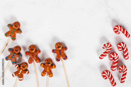 Christmas Cookie in the form of a gingerbread man and his cane, covered with colored icing sugar, on a wooden stick. White background. Top view. Copy space. New Year