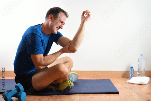 Man doing sport indoors complaining with elbow pain photo