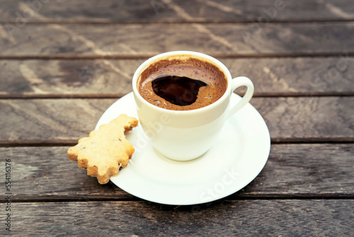 Top view on small cap of strong coffee espresso with cookie on wooden table.