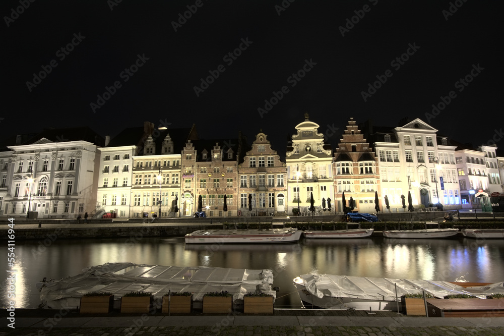 Famous Graslei quay with illuminated medieval guild houses reflecting in the water of river Lys in Ghent Flanders Belgium at night