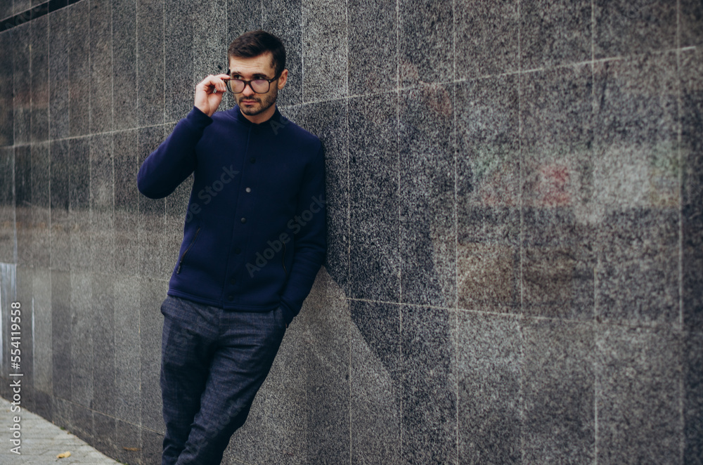 Obraz premium a man with glasses in his hand stands by the wall 