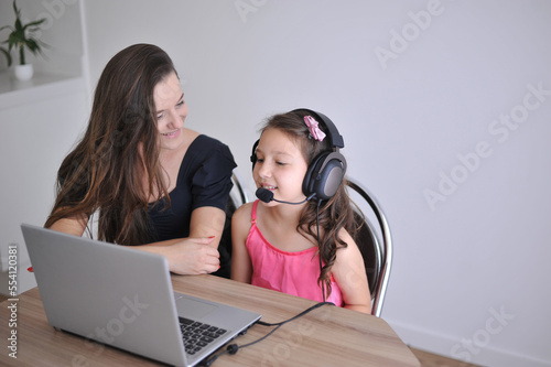 mãe e filha com computador portatil interagindo em casa 
