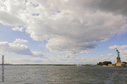 Beautiful view of Hudson River and Statue of liberty under white clouds on blue sky background. U.S.A
