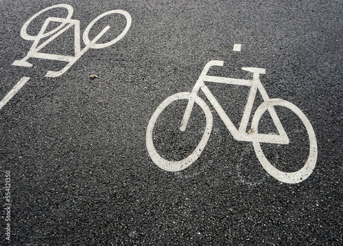 Fahrradweg mit Zeichen von zwei weißen Fahrrädern auf grauem Asphalt in Stadt am Mittag bei frost im Winter