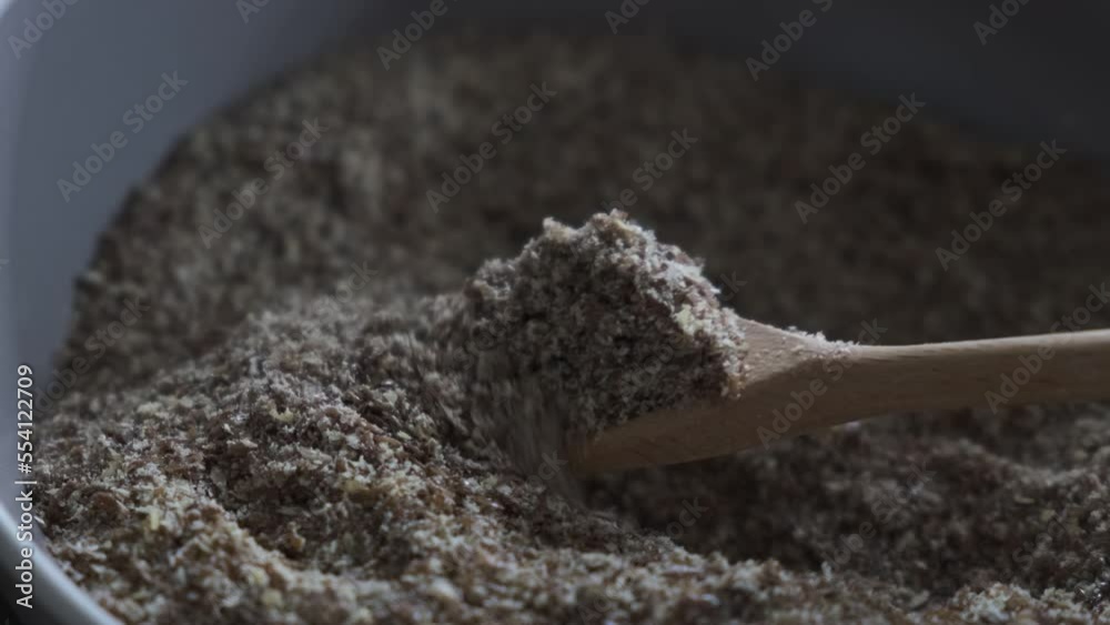 4k vídeo. Slow motion  Cuchara de madera cogiendo semillas de lino molino de un cuenco y semillas de lino enteras