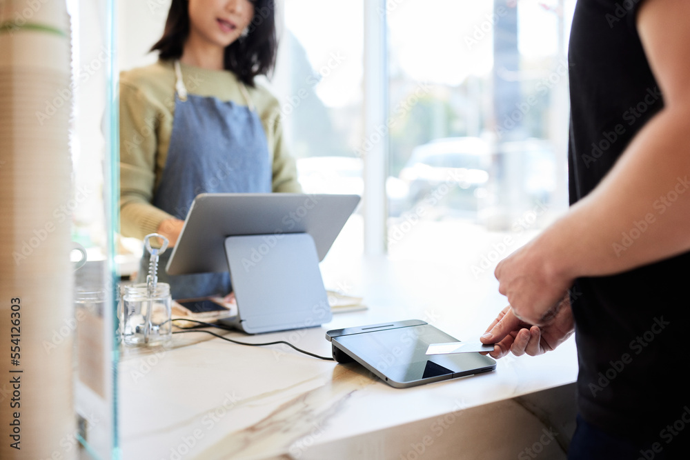 Mature male customer paying through credit card at checkout counter Mature male customer paying through credit card at checkout counter