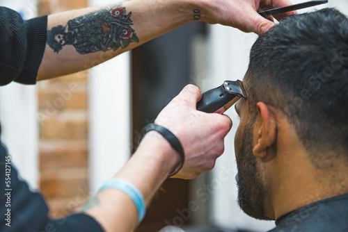 Close up of barber hands using hair clipper for a male haircut. High quality photo
