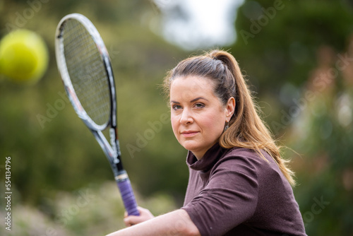 female tennis player practicing forehands and hitting tennis balls on a grass court in england © William