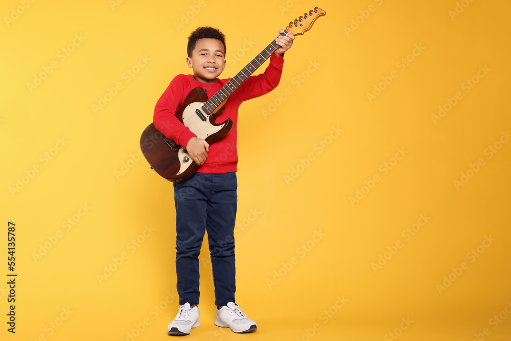 African-American boy with electric guitar on yellow background. Space for text African-American boy with electric guitar on yellow background. Space for text