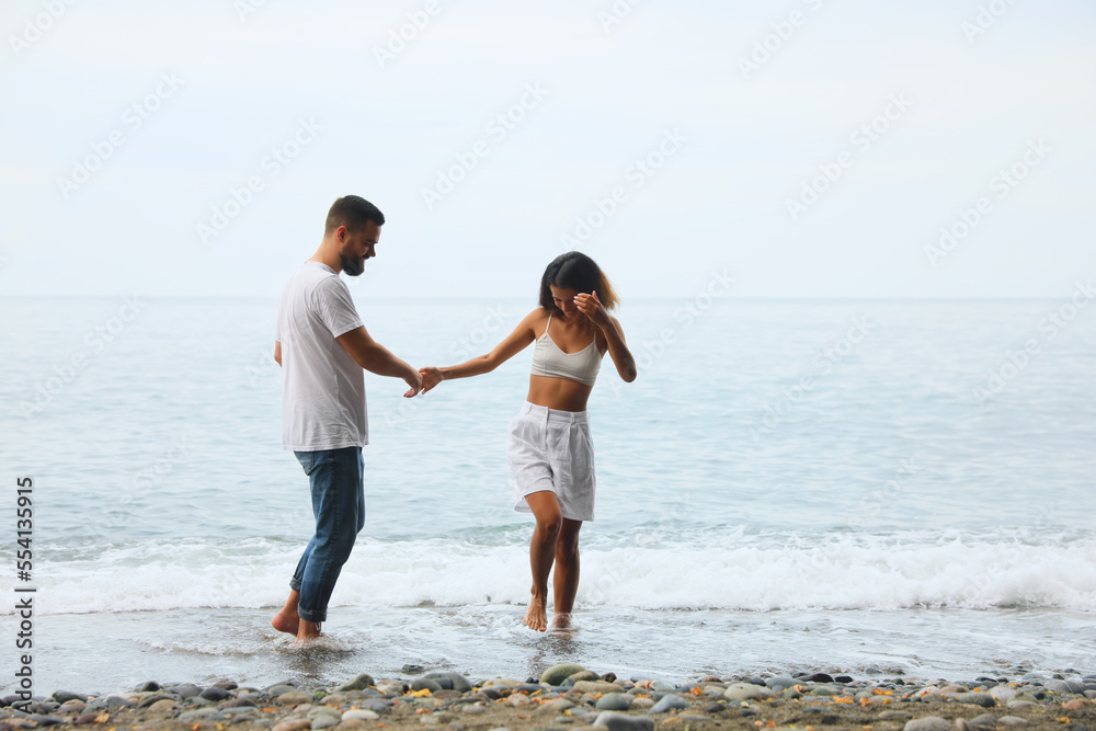 Happy young couple on beach near sea. Space for text