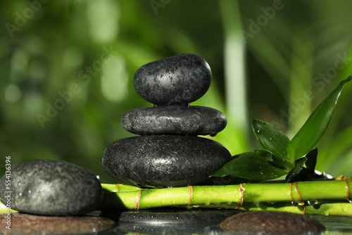 Wet stacked stones on bamboo stems against blurred background  closeup