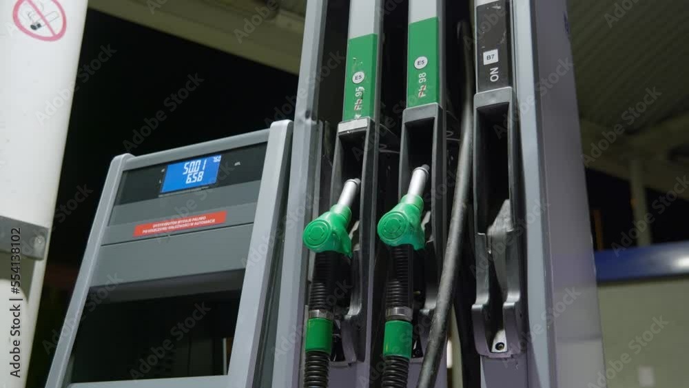 Person picks up fuel handle to begin refueling car's tank on a petrol station. Person picks up fuel handle to begin refueling car's tank on a petrol station.
