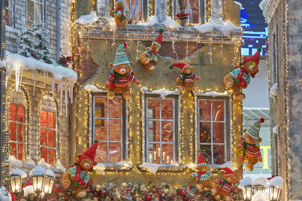 teddy bears in Santa Claus hats are crawling on the wall of a house decorated for Christmas. the concept of Christmas and New year