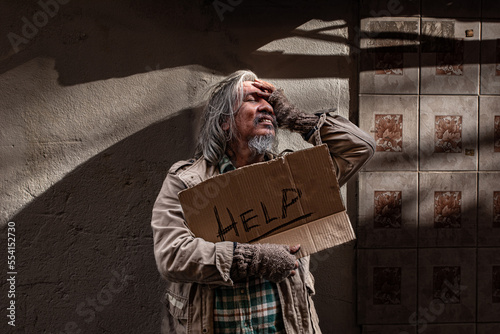Homeless poverty man holding signs for help against wall. old pity man with beard begging for money. society's economic problem abandoned hopeless elderly. pauper people on home sleep on footpath.