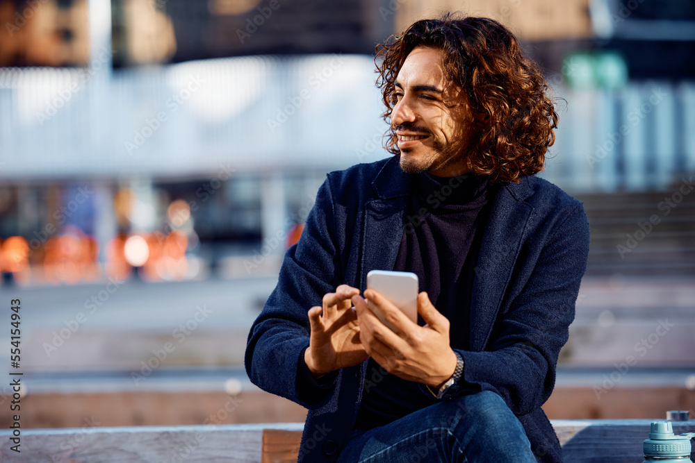 Young happy Hispanic businessman with smart phone in city. Young happy Hispanic businessman with smart phone in city.