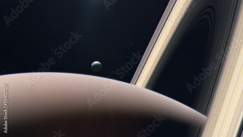 Saturn's Moon Enceladus Rising From Behind the Gas Giant Planet photo