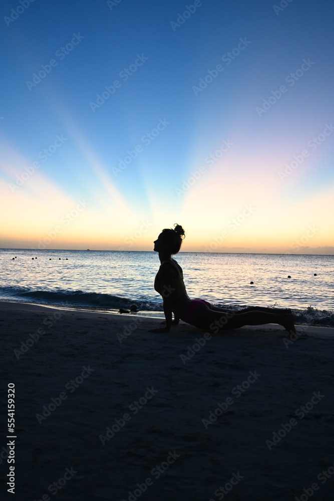 Cobra yoga pose - Woman doing yoga in silhouette in front of a sunset - Caribbean ocean - health and wellness