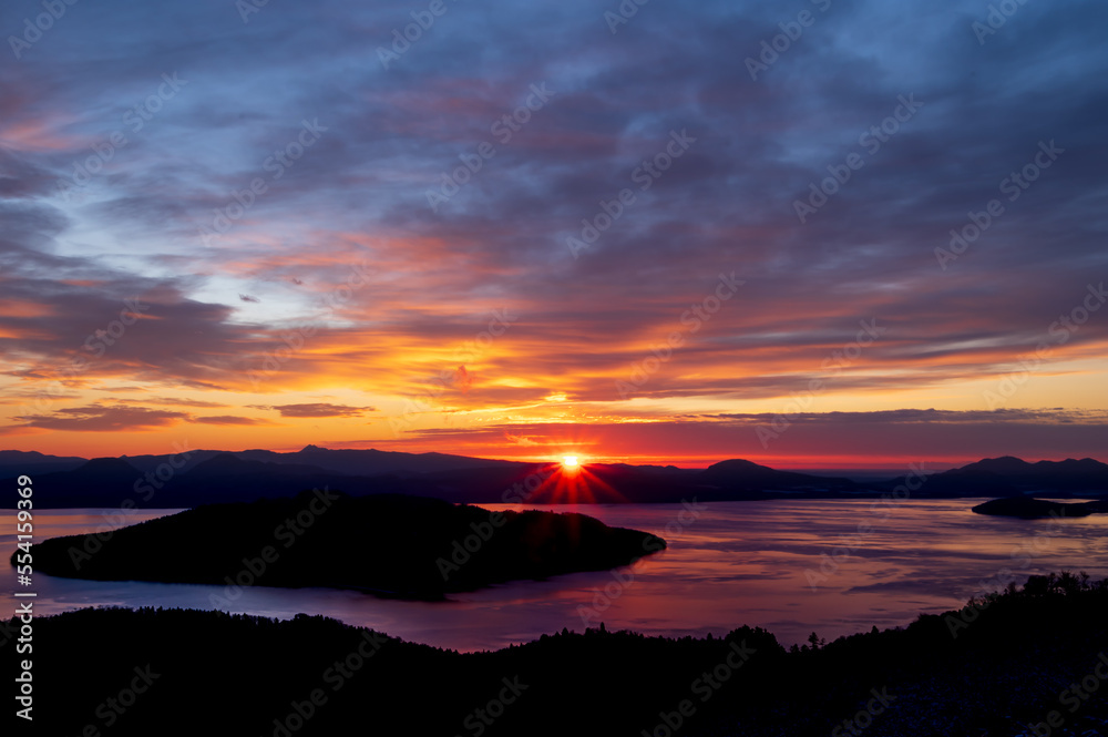  鮮やかな色彩の夜明けの空と上から見下ろす湖。日本の北海道の美幌峠の日の出。