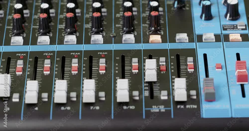 Closeup of a finger pushing a button on an audio mixer