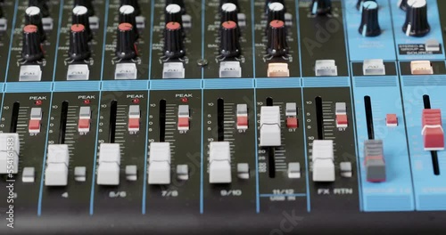 Closeup of a finger pushing a button on an audio mixer photo