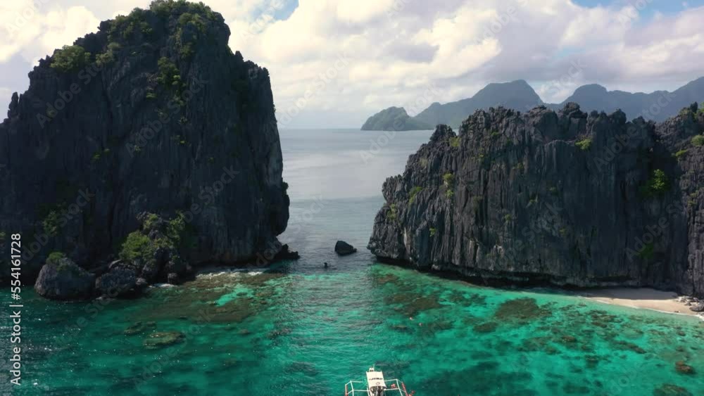 Aerial of huge limestone cliffs, turquoise water and natural archipelago with drone flying through rocks and small boats in El Nido, Palawan, Philippines. Aerial of huge limestone cliffs, turquoise water and natural archipelago with drone flying through rocks and small boats in El Nido, Palawan, Philippines.