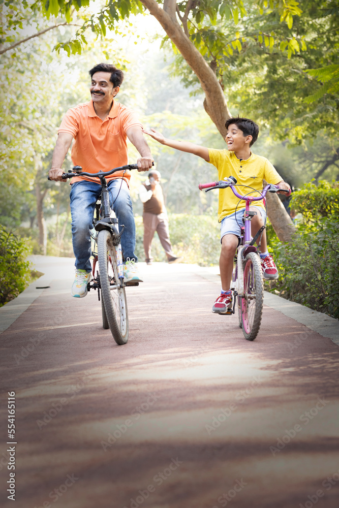 Young father and son having fun riding bicycle.