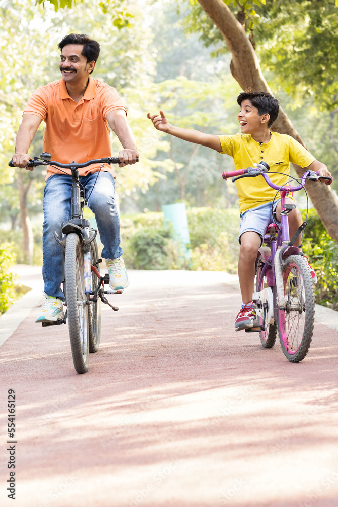 Fototapeta premium Young father and son having fun riding bicycle.