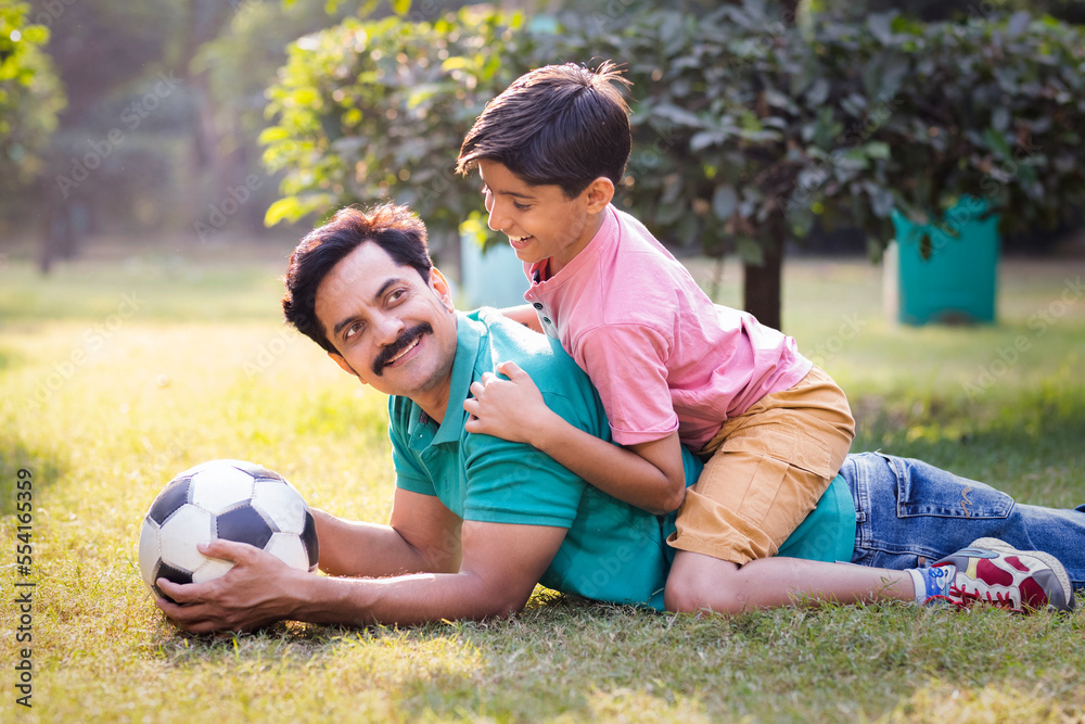 Father and son having fun while playing with football at park. Father and son having fun while playing with football at park.
