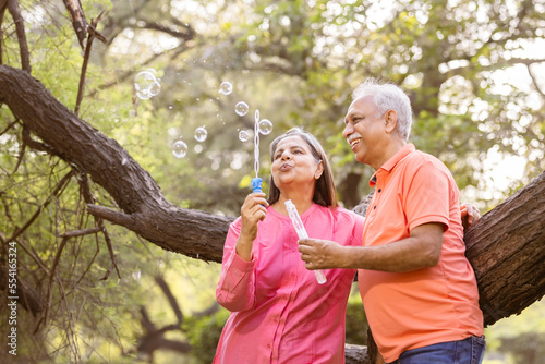 Photography Active senior couple having fun blowing bubbles at park.