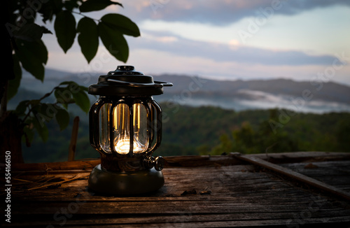 Close-up of a lantern on the bamboo table in the morning light before sunrise with a mountain view for the start of a new day.