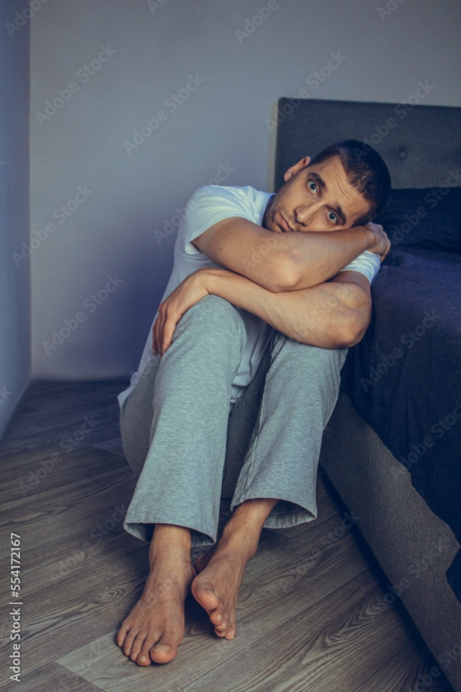 Dramatic lifestyle portrait of a handsome guy in his 30s and 40s, sitting sadly on the bed, feeling anxious and suffering from depression. Attractive depressed and upset man in home bedroom. Dramatic lifestyle portrait of a handsome guy in his 30s and 40s, sitting sadly on the bed, feeling anxious and suffering from depression. Attractive depressed and upset man in home bedroom.