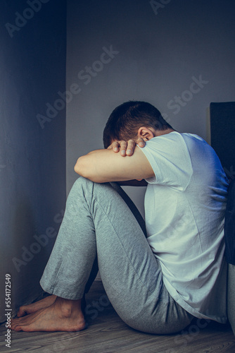 Dramatic lifestyle portrait of a handsome guy in his 30s and 40s, sitting sadly on the bed, feeling anxious and suffering from depression. Attractive depressed and upset man in home bedroom.