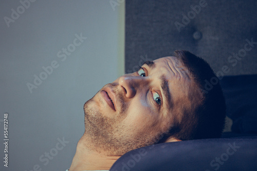 Εκτύπωση καμβά Dramatic lifestyle portrait of a handsome guy in his 30s and 40s, sitting sadly on the bed, feeling anxious and suffering from depression