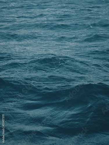Dark blue-green color of water surface with waves in middle of endless deep sea. Endless wavy expanse of blue sea water. Dark blue waves in deep ocean. Raging aquamarine waves on surface of the water. © Pavel