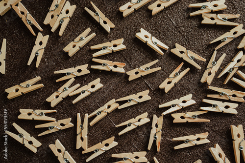 wooden clothespins for clothes scattered on a brown background