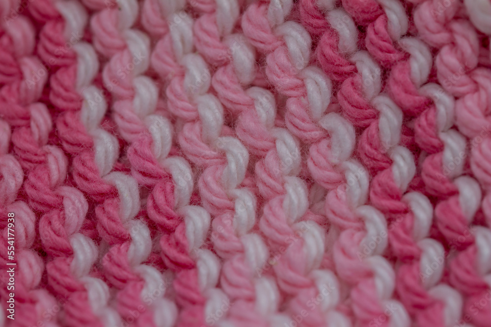 Macro defocused abstract texture background of a hand-knitted pink and white color cloth in a garter stitch pattern