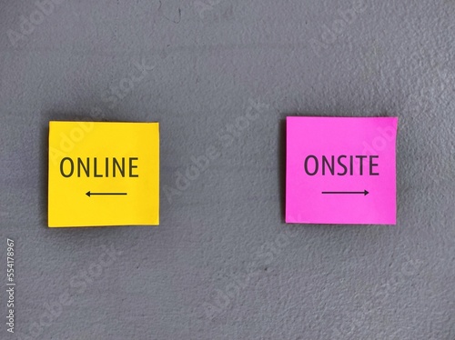 Yellow and pink stick note on wall with direction to ONLINE and ONSITE, education and work choices in pandemic, digital revolution turned conventional working and studying onsite to online or hybrid 
