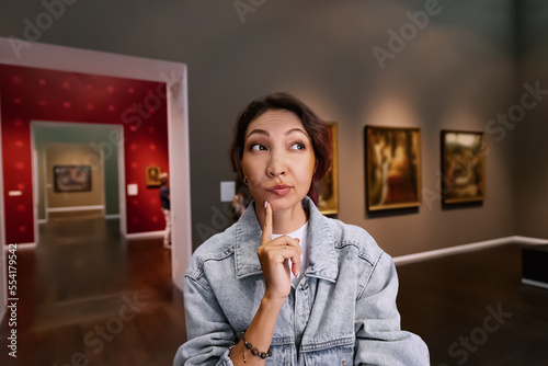 Photo A girl critic and expert visitor to a museum or art gallery thoughtfully looks a