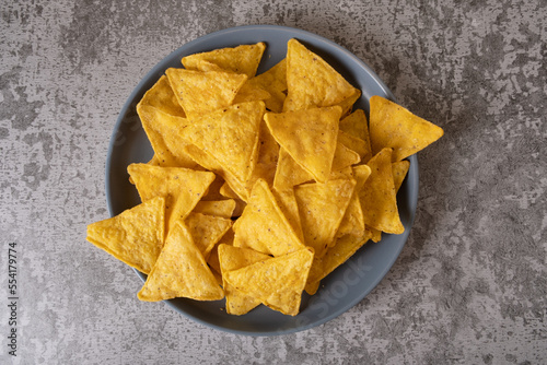 Mexican nacho corn chips on a blue plate on a concrete gray background.