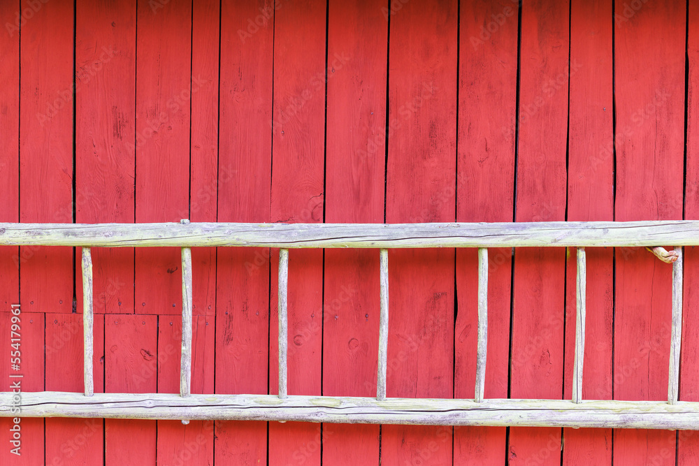 Old wooden ladder on a red wooden wall Old wooden ladder on a red wooden wall